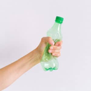 main qui ecrase une bouteille en plastique